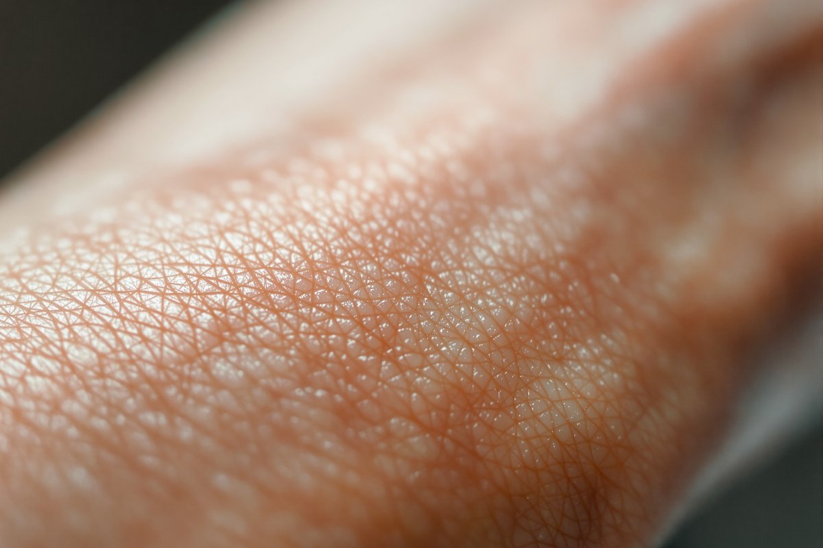 An extreme macro close-up of healthy human skin texture on a forearm showing fine lines, pores and soft fine hairs