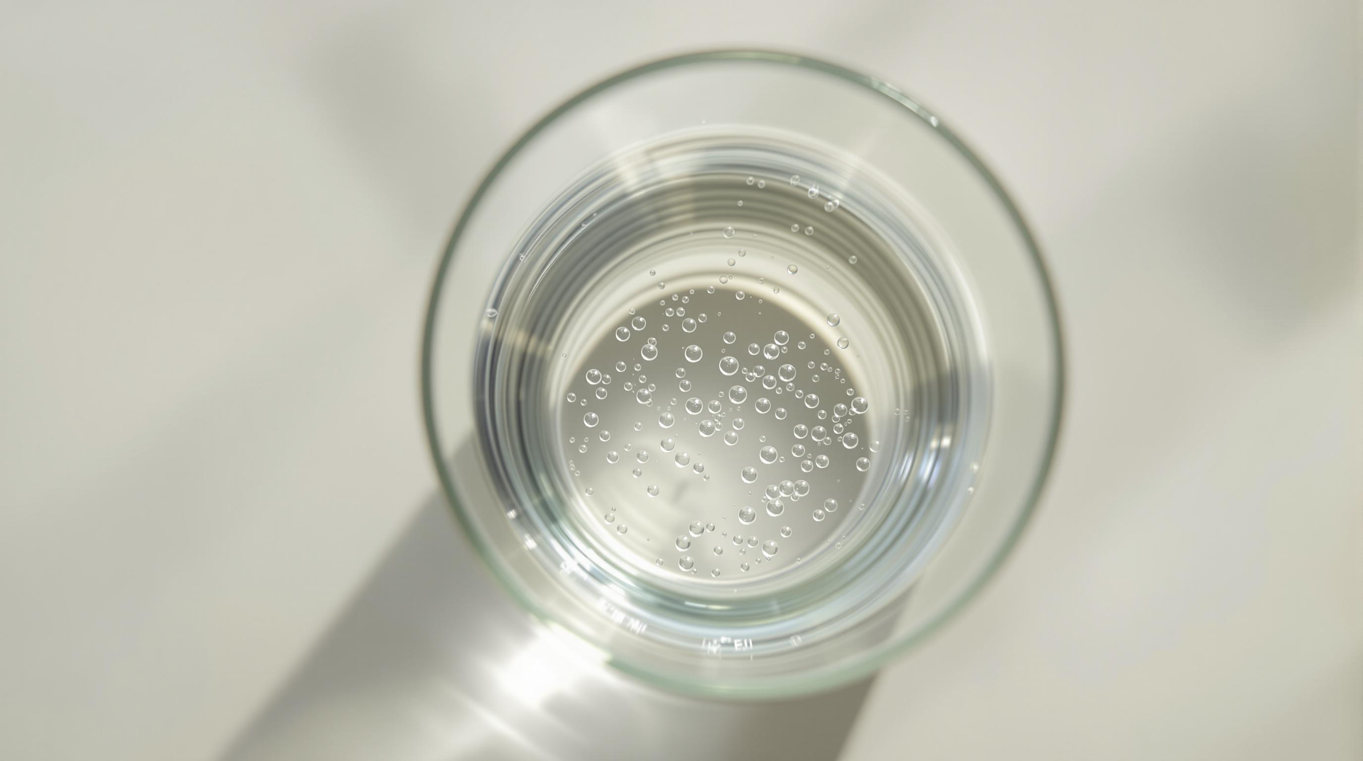 Uncooked white rice being rinsed under running water in a glass bowl