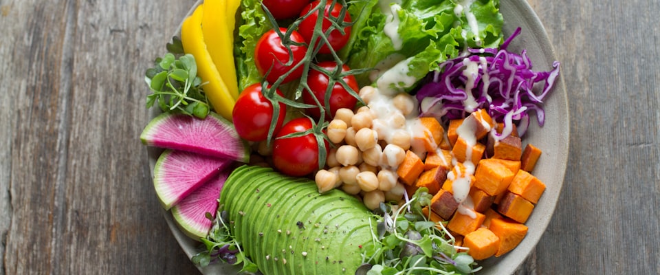 Fresh whole foods on a wooden kitchen surface — vegetables, grains, and glass containers representing gut-healthy, plastic-free eating