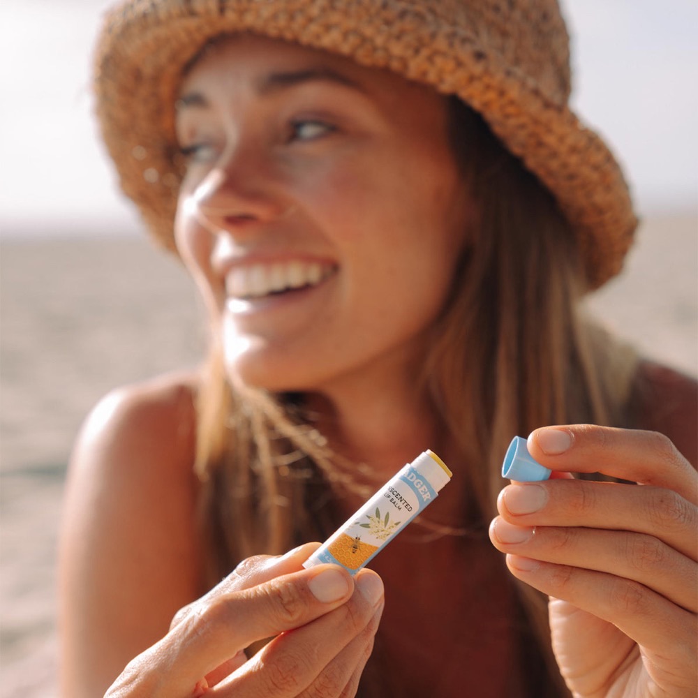 A person applying Badger Certified Organic Classic Lip Balm — five organic ingredients, USDA Organic, B Corp