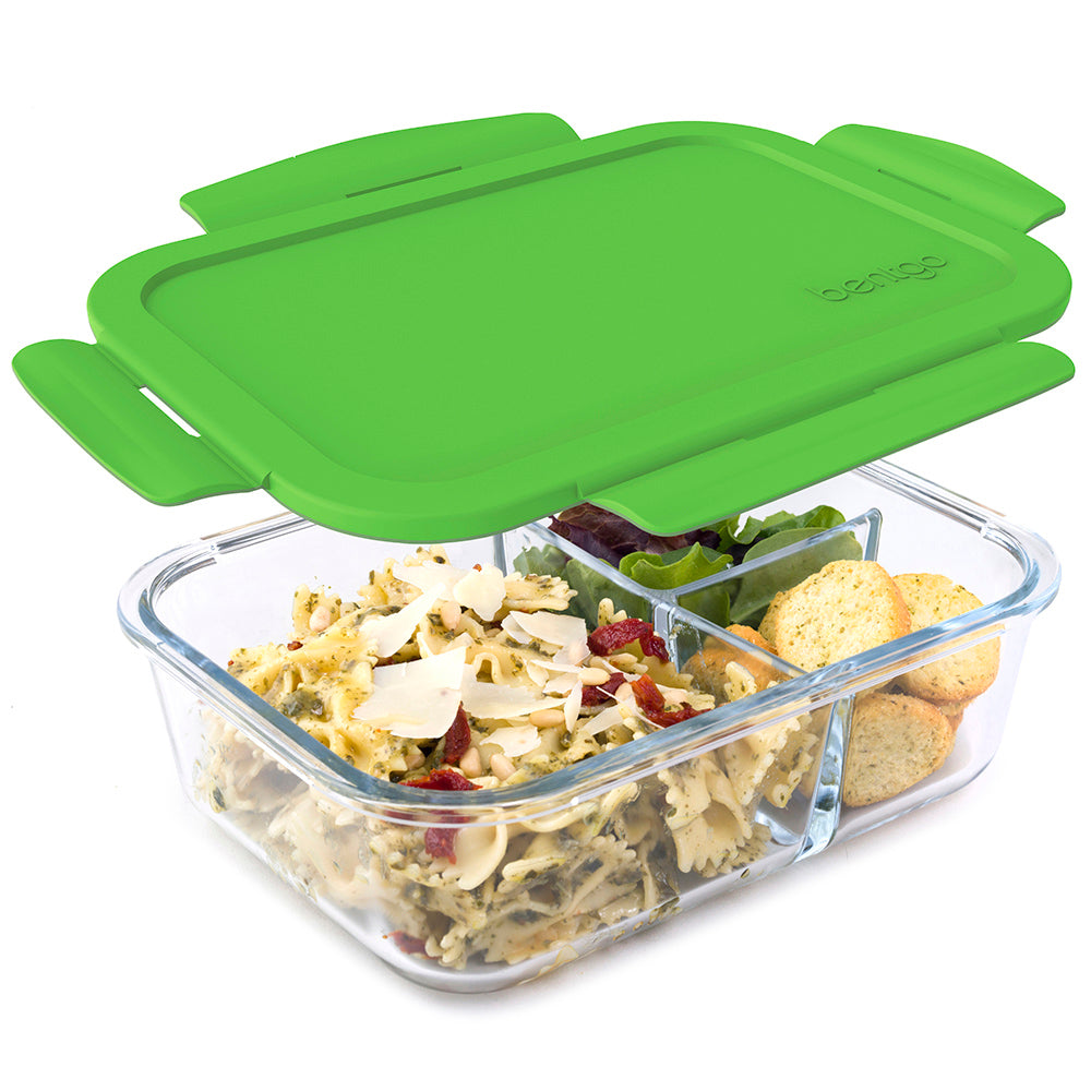 Bentgo Glass lunch container — clear borosilicate glass body with green silicone lid, holding pasta salad, greens, and crackers in three compartments