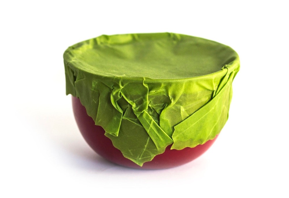 Etee handmade beeswax food wrap in green stretched over a red bowl, showing the hand-molded seal