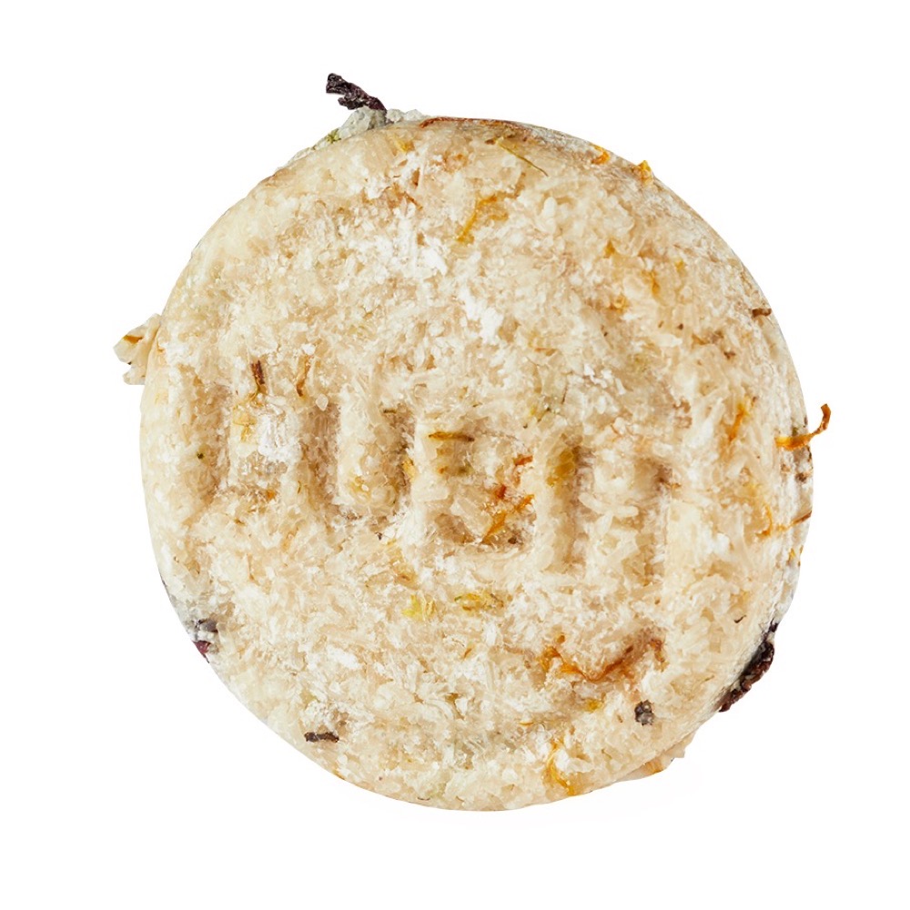 Lush Soak and Float shampoo bar — round oatmeal-coloured bar embossed with the LUSH logo, sold naked with no packaging