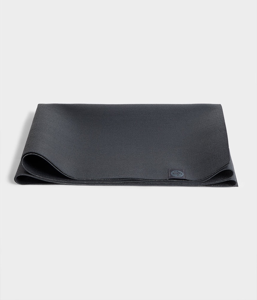 Manduka eKO Superlite travel yoga mat in charcoal, folded flat — 1.5mm natural rubber, PVC-free, weighs 2.2 lbs