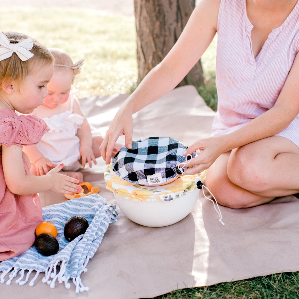 Marley's Monsters reusable cotton bowl covers — a gingham and a floral cover cinched over nested bowls at a picnic