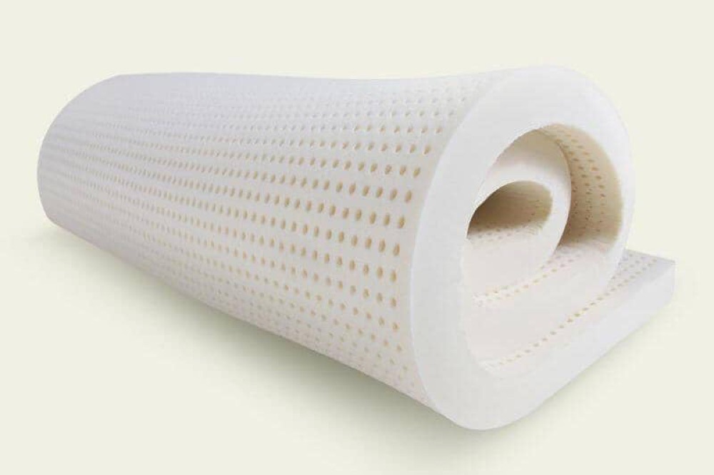 PlushBeds Natural Latex Topper — a rolled slab of pin-cored organic Dunlop latex