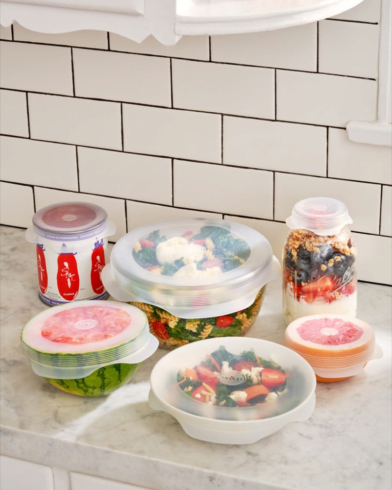 W&P silicone stretch lids set sealing bowls of salad, a pasta dish, a can, and a mason jar on a kitchen counter